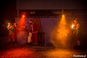 aktorzy w strojach mikołaja i elfów wykonują świąteczny pokaz fireshow