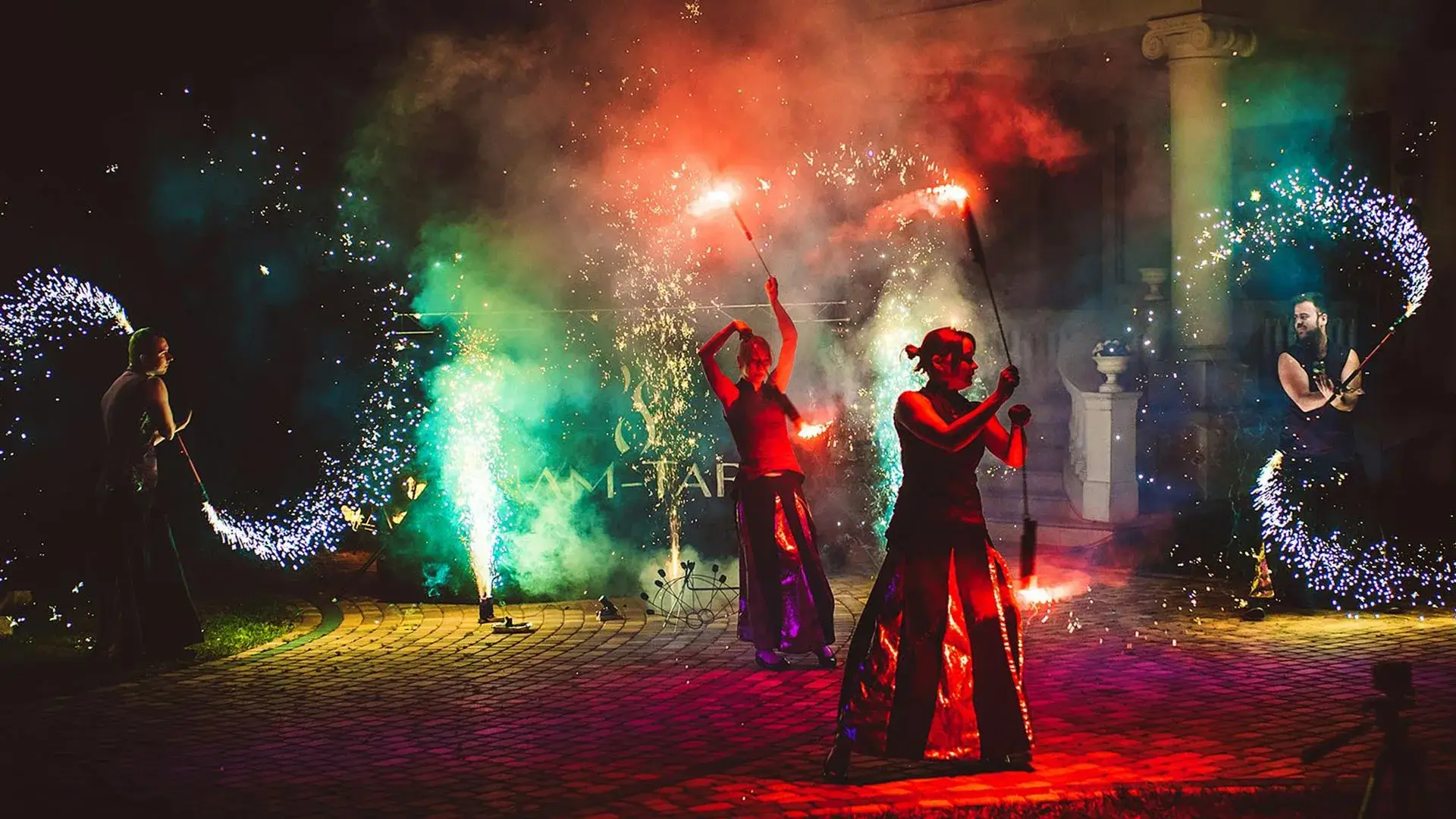 tancerze ognia wykonujący taniec z kolorowymi efektami pirotechnicznymi