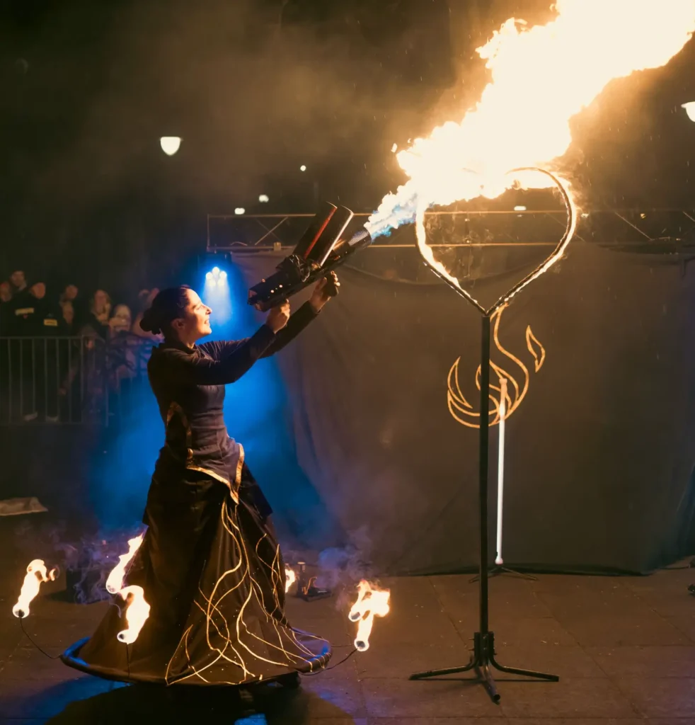 artystka w płonącej sukni zapalająca płonące serce miotaczem ognia podczas pokazu fireshow