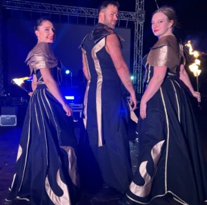 trzech artystów pozujących tyłem z płonącymi rekwizytami w rękach, po pokazie fireshow